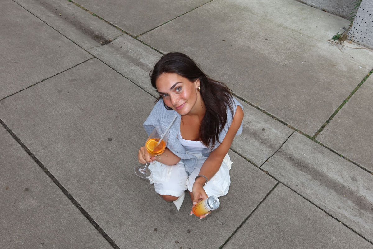 Vrouw op de stoep met een glas Spritz en een blikje Bald Brewer